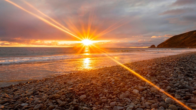 Sunbeams reaching from glowing sun over the ocean.