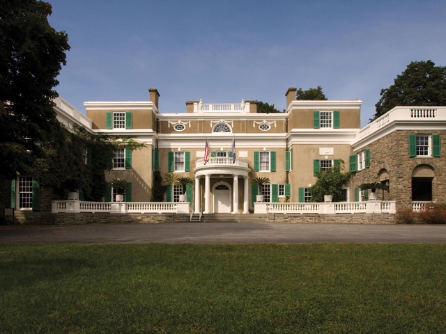 A stucco and fieldstone house with white trim and circular portico.