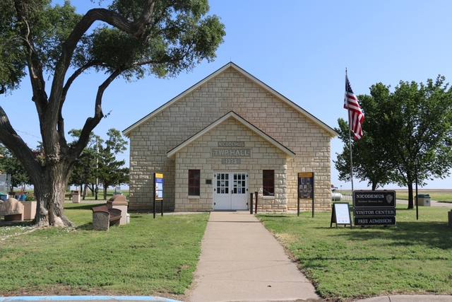 A limestone brick building with grass and trees around it