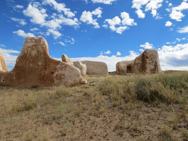 Ruins of adobe building under a blue sky with white clouds.