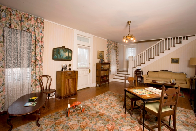 A view of the formal living room features a tricycle, table and chairs, and radio