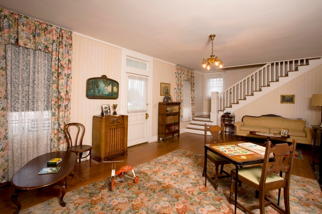 A view of the formal living room features a tricycle, table and chairs, and radio