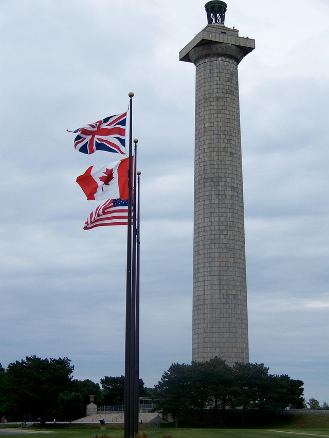 The Memorial Column with the United Kingdom, Canadian, and US Flags flying from poles on the lawn.