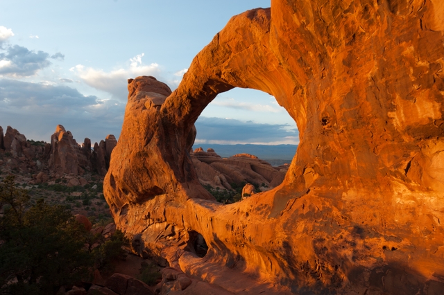 a broad, red arch with rock pinnacles in the background
