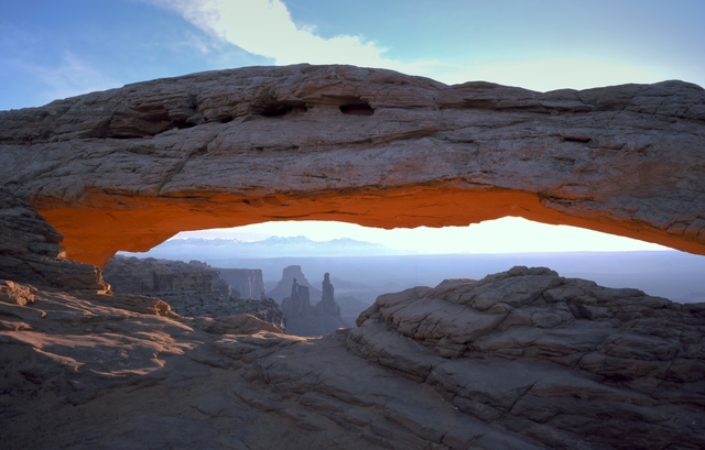 a broad stone arch with rock pinnacles in the distance