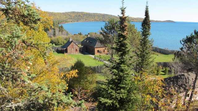 Three log buildings with Lake and point of land in background.