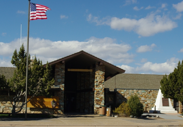 The Flag flies over Golden Spike National Historical Park's Visitor Center, with trees and monument
