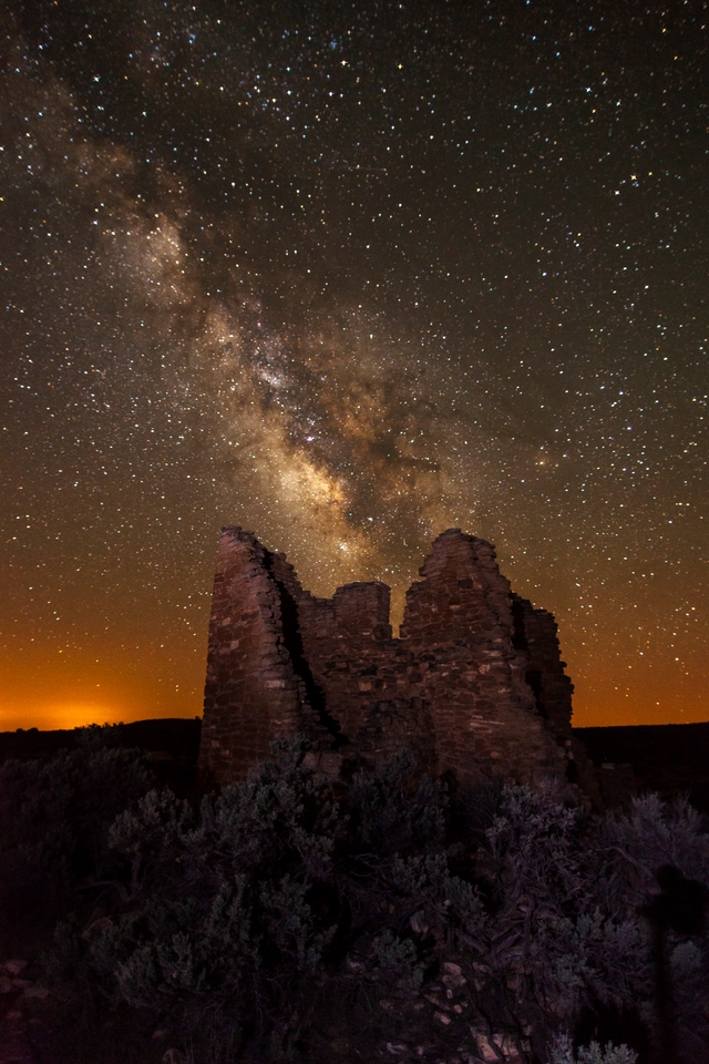 a stone structure at night with the Milky Way arcing overhead