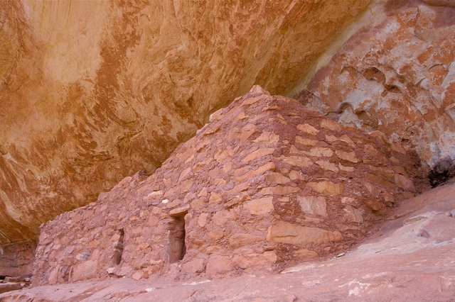 a stone structure below a rock alcove