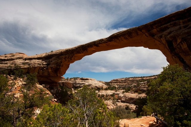 a broad natural bridge with clouds in the sky