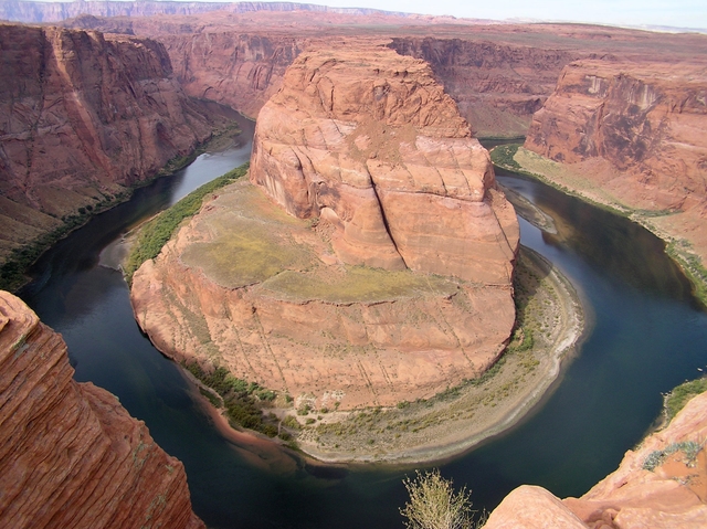 Green river winds through high cliffs.