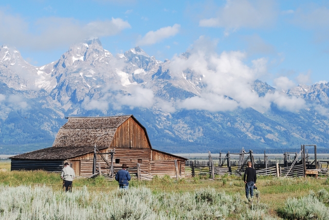 Historic Moulton Barn with visitors and the Teton Range beyond.