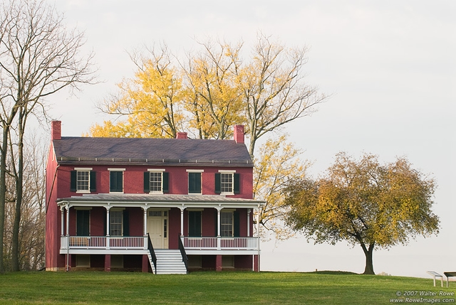 Federal style house with trees behind it during the fall season.