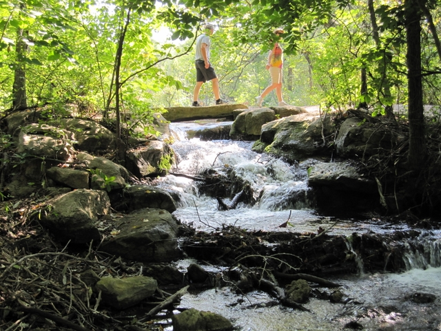 Two people hiking over a water feature