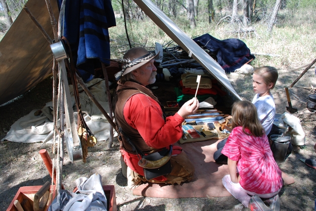 Living history interpreter explaining the life of a trapper/trader to young visitors