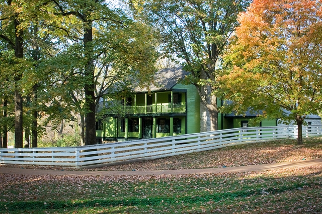 View of house with fence. Autumn colored leaves on trees