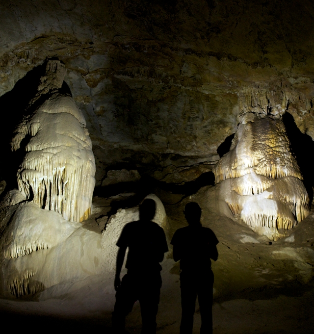 Two cavers inspect a series of calcite cave formations