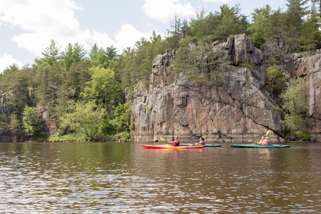 Kayakers pass impressive cliffs.