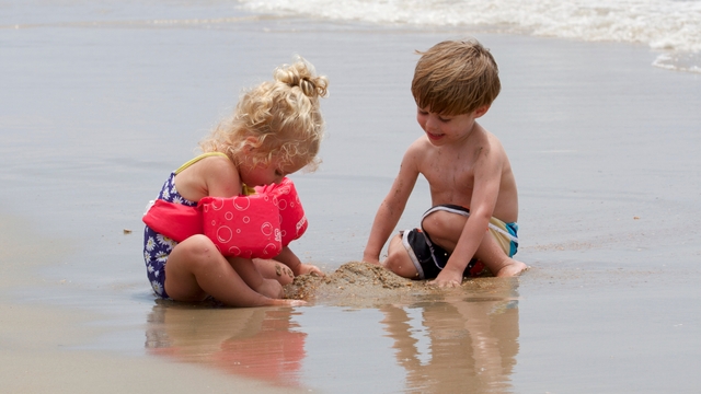 Two kids play in the sand.