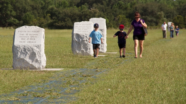 Visitors walk along the flight line where Wilbur and Orville Wright flew and landed.