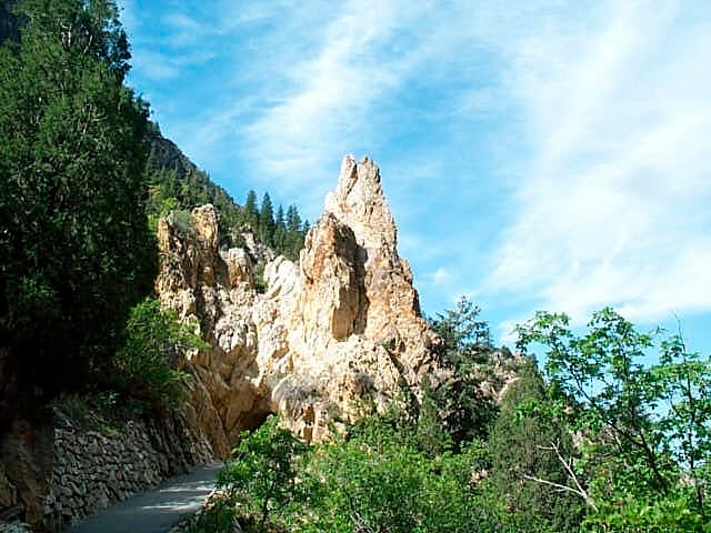 White-orange quartzite surrounded by greenery stands against a blue sky