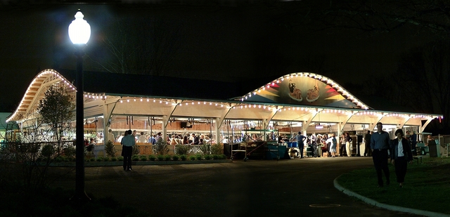 outdoor scene of open dance pavilion illuminated and evening dance crowd inside.