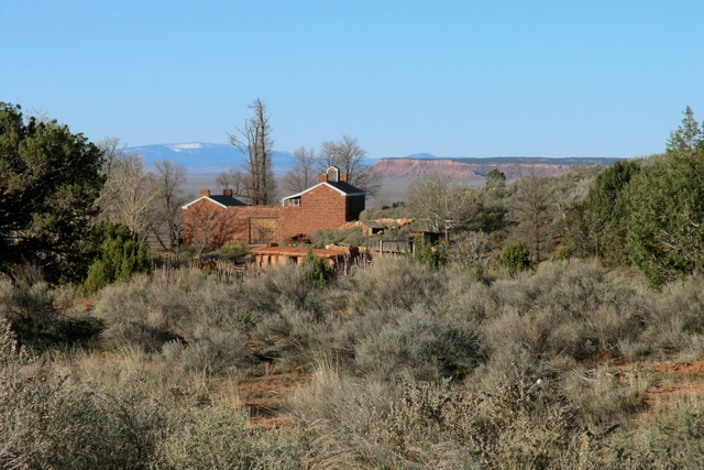 A sandstone fort rests between desert scrub in the foreground and a mountain in the distance.