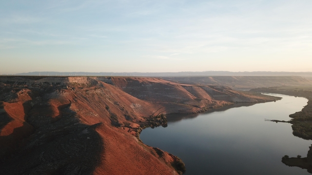 Steep, rocky bluffs line a river, awash in warm sunset colors