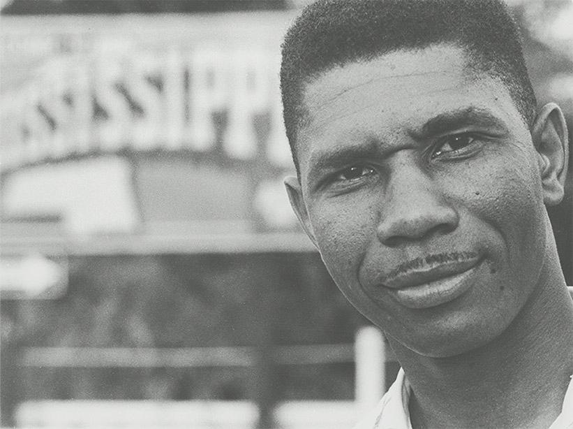 Close up black and white image of a black man with a pencil mustache.