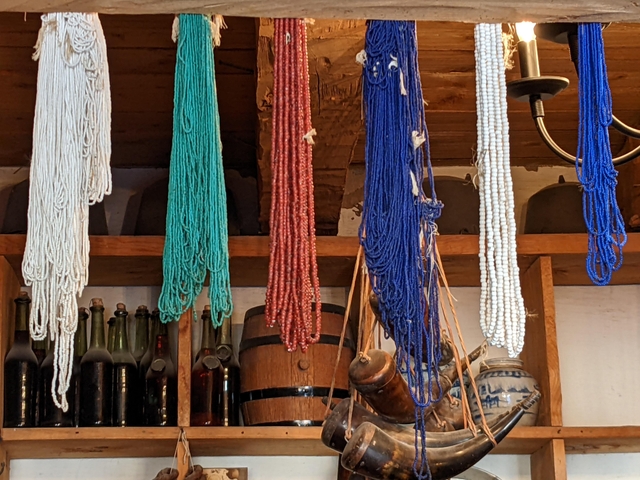 bundles of glass trade beads tied together hang from a wooden rafter