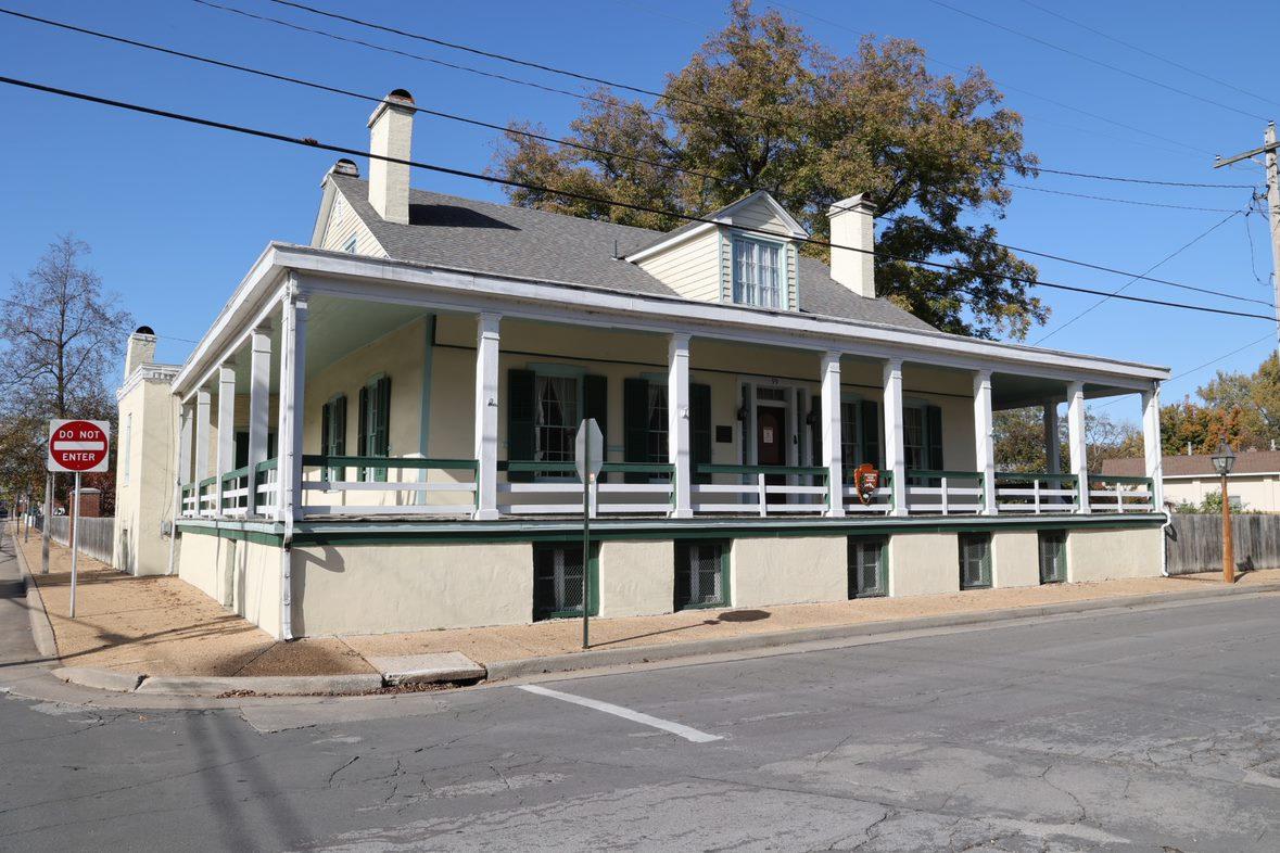 Cream colored house with a covered porch on a street corner.