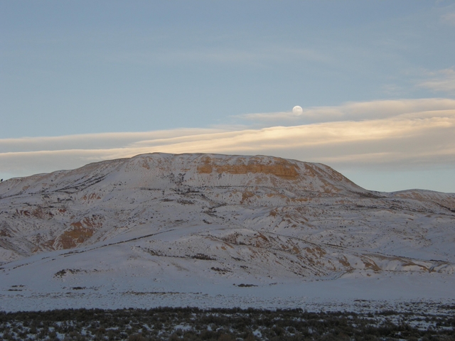 The moon over a snow-covered butte
