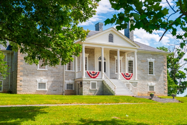 American flag bunting hangs from the porch on a limestone building with a white portico.