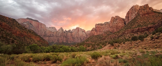 The sun sets behind large red and white towers of sandstone.
