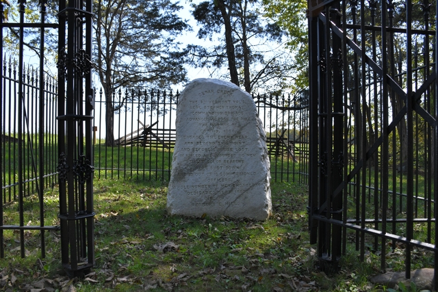 A rough marble monument in an iron-fenced enclosure commemorates Civil War combat.