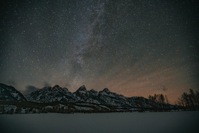A starry night sky with snowy mountains in the foreground