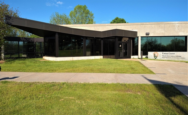 Front Entrance of Visitor Center and Arrowhead on sign reading "Wilson's Creek National Battlefield"