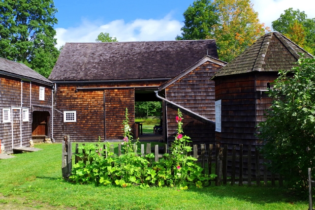 An wooden barn with the slider door open and a wooden fence around the sides.