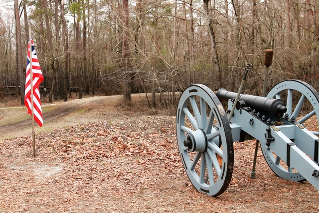 Cannon on a hill on a winter day. American flag to the left of the cannon