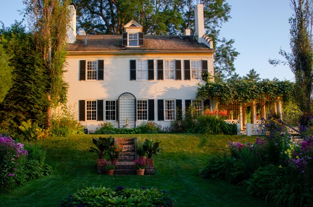 historic white brick house with flower gardens