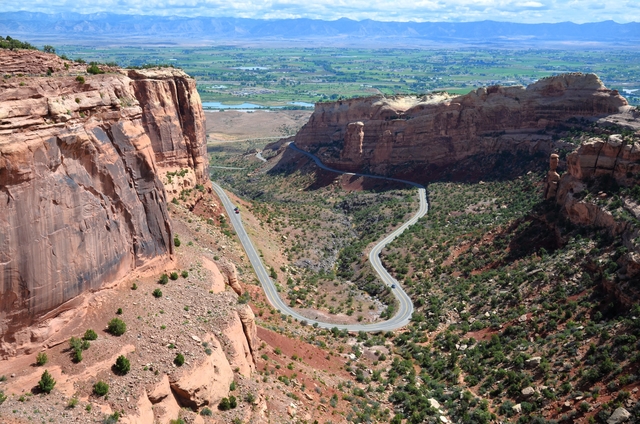 Looking down from canyon rim at a U shaped portion of road entering and exiting the canyon