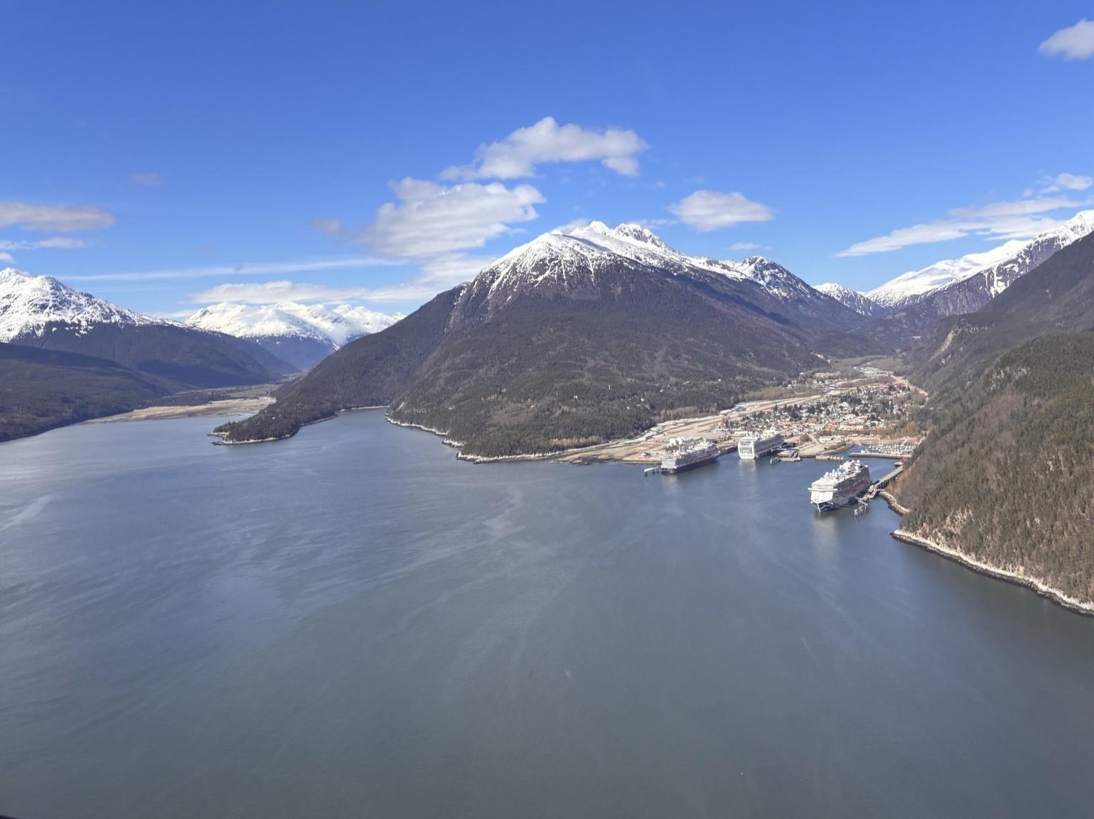 Aerial image of two inlets in a deep fjord, with a small city and large cruise ships tucked in one