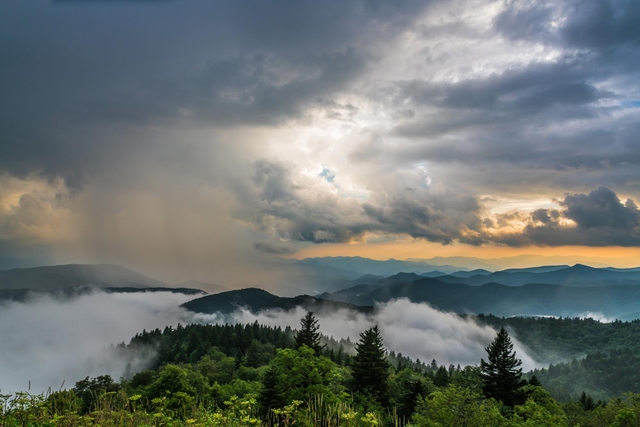 Storm clouds breaking over the mountains at sunset, with fog hugging the valleys