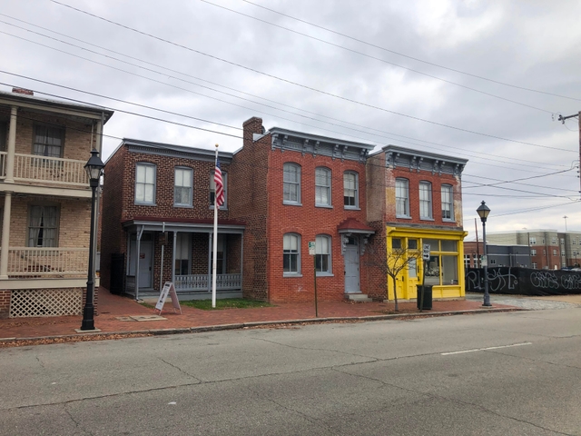 3 red brick, two-story buildings, with a US flag flying and an overcast sky