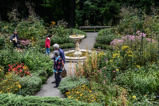 formal four square garden in full bloom from above with two people looking at flowers