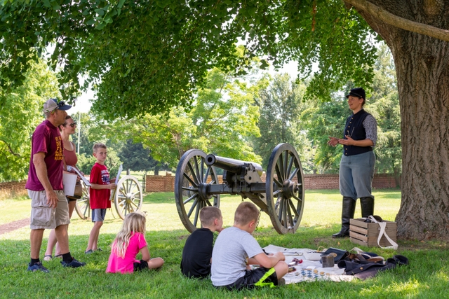 A living historian dressed as a US Civil War soldier speaks with a family outdoors.