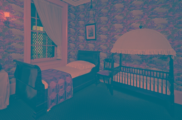 colored photograph of nursery with a sleigh bed and crib adjacent to bed.