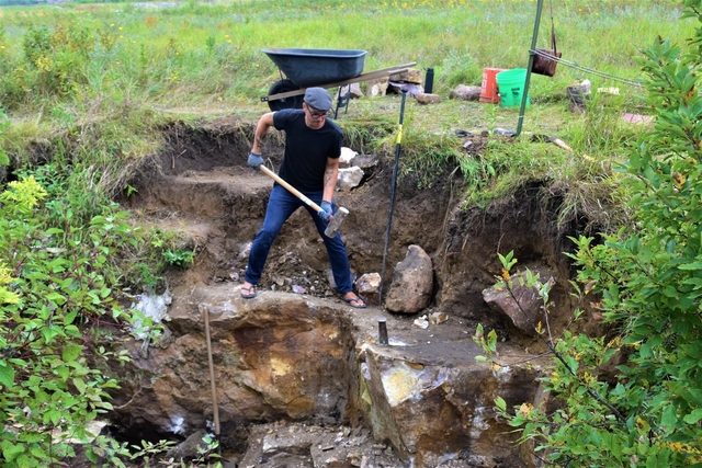 A man in a quarry pit holding a sledge hammer