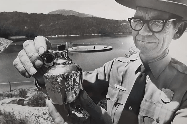 Park ranger with flat hat holding a small commemorative jug