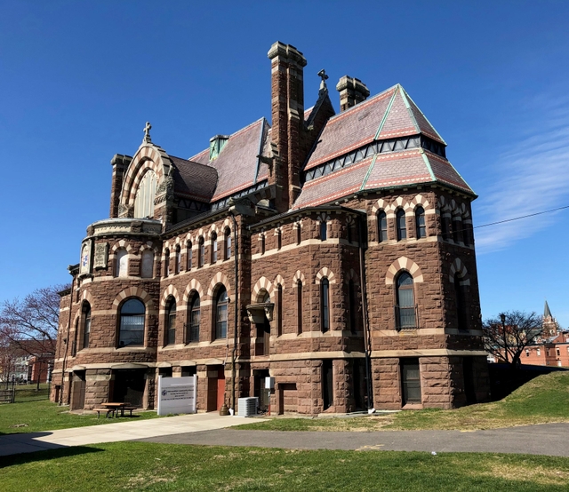 A tan and brown building with numerous design elements meant resemble a ship, against a blue sky.